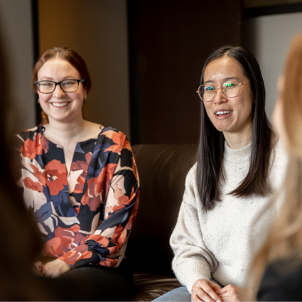 Two women in glasses smiling chatting with colleagues