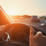 Person driving vehicle with two hands on steering wheel looking at traffic ahead